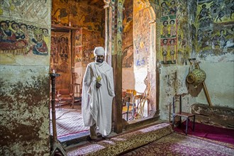 Orthodox priest inside Abreha We Atsbeha rock-hewn church decorated with medieval wall paintings near Wukro