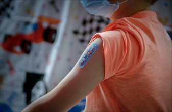 A boy has a patch on his upper arm after being vaccinated with the BioNTech Pfizer vaccine for children at a COVID-19 vaccination and testing centre at Autohaus Olsen in Iserlohn