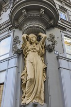 Stone girl figure as a support on a historic facade