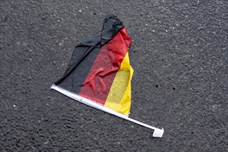 A flag of Germany lies on a wet street in Berlin