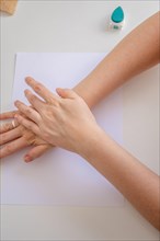 Top view of a woman's hands pressing a rubber stamp on a blank sheet of paper