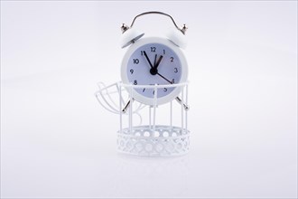 White color alarm clock on bird cage on white background