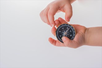 Child hand holding a compass on a white background