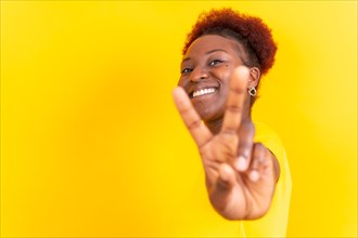 Young african american woman isolated on a yellow background smiling with the victory gesture