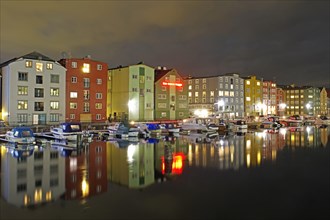 Brightly lit houses and pleasure boats reflected in a harbour basin at night