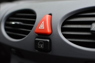 Close up of a triangular red hazard flasher button inside car interior