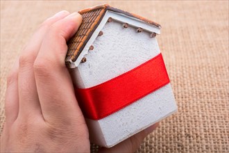 Little model house and a hand on a light brown color background