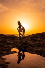 Silhouette of mother and son walking in the sunset on the beach of Tacoron in El Hierro