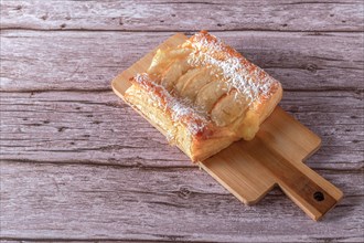 Top view of an apple tartlet with grated coconut on a wooden board