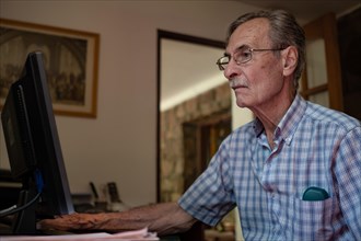 Older man very concentrated in front of computer at home
