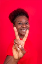 Young african american woman isolated on a red background smiling with the victory gesture