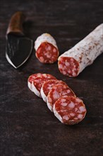 Slices of fermented salami sausages on dark background