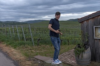 Youth with mobile phone in front of the vineyards in Kaiserstuhl