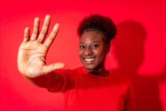 Young african american woman isolated on a red background with gesture stop from fingers