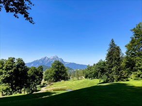 Golf Course with Mountain View and the Moon in a Sunny Summer Day in Burgenstock