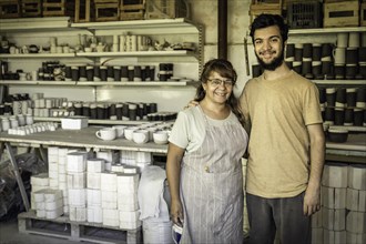 Wife and son smiling and looking at the camera in the ceramics studio. Family business