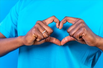 Young african american woman isolated on a blue background smiling and heart gesture