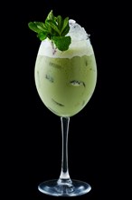 Iced matcha tea in a wine glass on black background