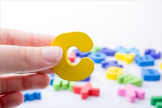 Letter C in hand beside colorful alphabet letter blocks scattered randomly