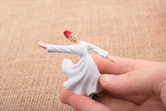 Hand holding a white color Sufi Dervish figurine in hand