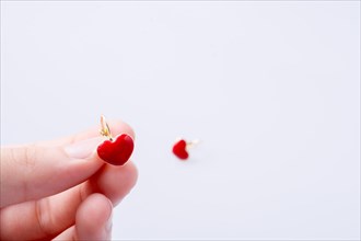 Red color heart shape earring in hand on white