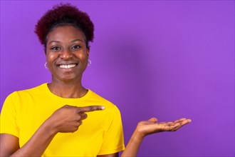 Young African American woman isolated over purple background smiling and pointing