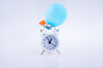 Alarm clock and a balloon with a heart on white background