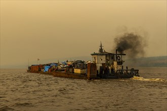 Overloaded riverboat on the Congo river at sunset