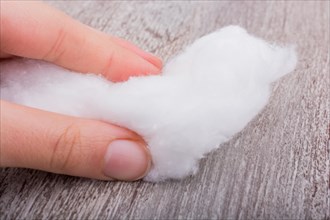 Hand holding some cotton in hand on a grey background