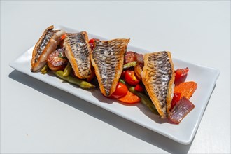 Fried fish with vegetables on a white tray