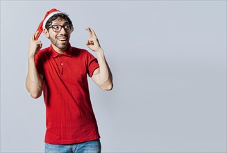 Guy with christmas hat making a wish on isolated background