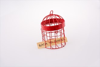 Note about school placed in a red color bird house cage with metal bars