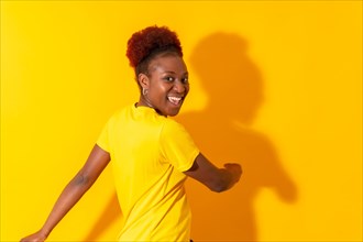 Young african american woman isolated on a yellow background smiling and dancing