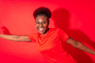 Young african american woman isolated on a red background smiling and dancing