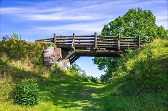 Small wooden bridge over a field and hiking path in front of Laeckoe Castle at Lake Vaenern