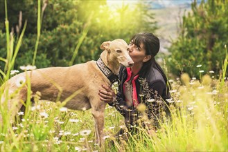 Beautiful woman kissing her dog outdoors. Girl with her dog. Cute dog loves her owner