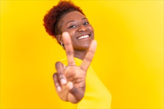Young african american woman isolated on a yellow background smiling with the victory gesture