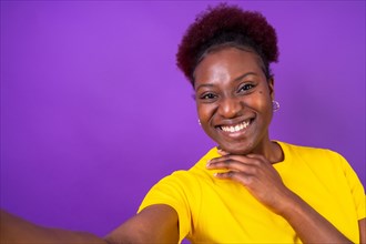 Young african american woman isolated on a purple background smiling and making a selfie