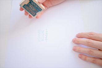 Close-up of a woman pressing a stamp with the phrase sustainable packaging on a white sheet of paper
