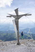 Mountaineer at the summit cross on the Hochkoenig