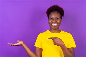 Young African American woman isolated over purple background smiling and pointing