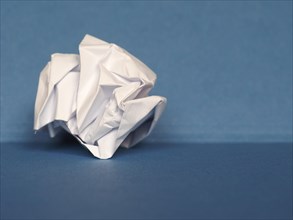 Crumpled paper over blue background with copy space