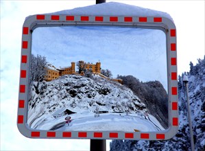 A traffic mirror shows Hohenschwangau Castle in winter