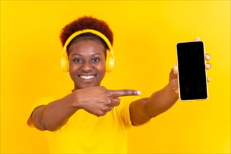 Young african american woman isolated on a yellow background with mobile pointing gesture