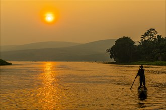 Man on his dugout canoe at sunset on the Congo river
