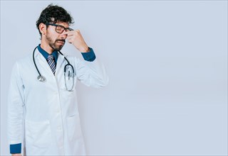 Stressed and tired doctor isolated with copy space. Tired young doctor touching nose isolated