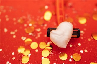 Razor with heart shaped shaving foam. Bright red background with silver glitters and gold round confetti. Copy spase. Bodycare and skincare concept. Close up