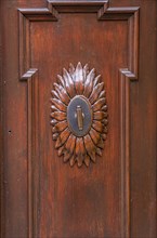 Decorative element with handle on a wooden door