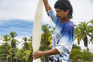 Fisherman holding his net with palm trees in the background