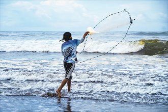 Rear view of a fisherman on the shore casting his net